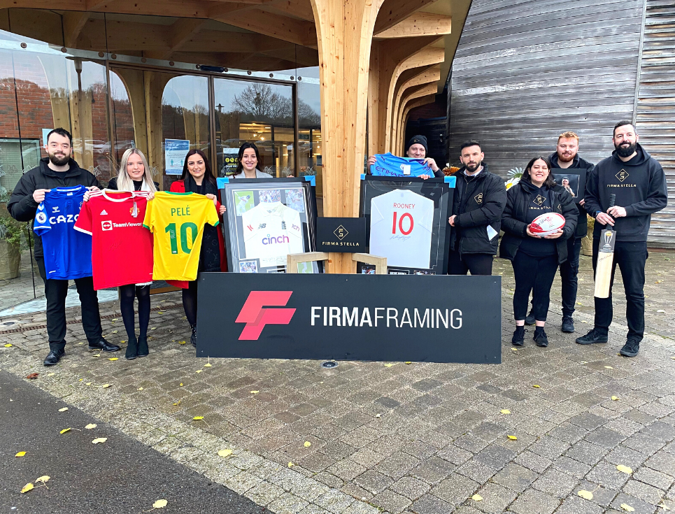 A group of people stand outside St Richard's Hospice holding various pieces of signed sports memorabilia