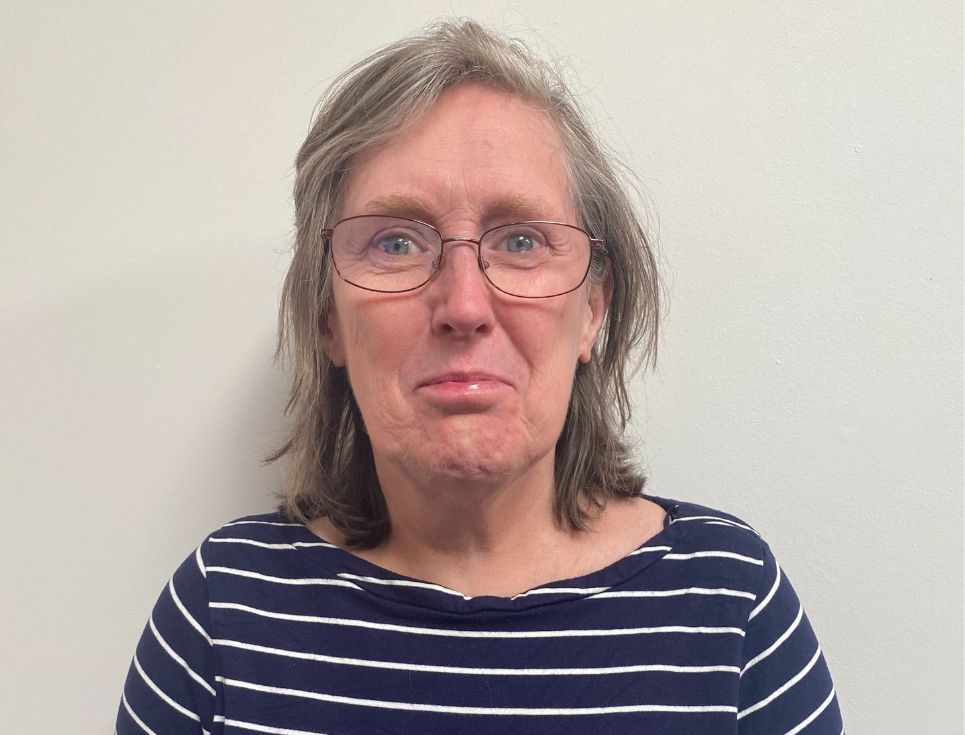 Gillian pictured against a plain white background. She is wearing a navy blue and white striped top.